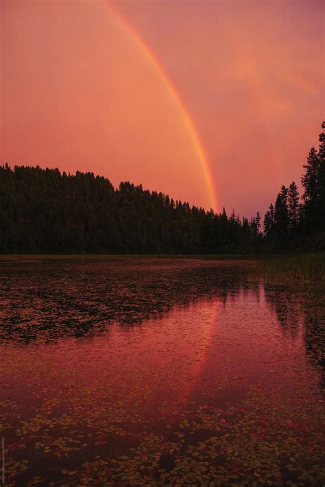 "Rainbow With Reflection At Lake During Sunset." by Stocksy Contributor "Justin Mullet" - Stocksy