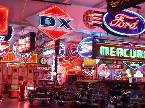 an assortment of neon signs and cars in a building with lights on the sides of them