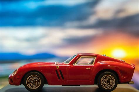Red Ferrari toy car on platform with sunset background - Creative Commons Bilder