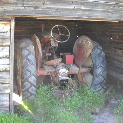 an old tractor sitting in the middle of a garage with it's front wheel missing