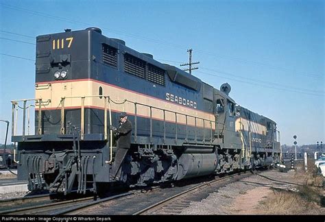 a train engine carrying carts down a track next to a loading dock and ...