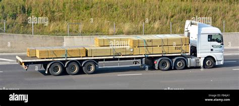 Side view of hgv lorry truck haulage business with articulated flatbed articulated trailer load ...