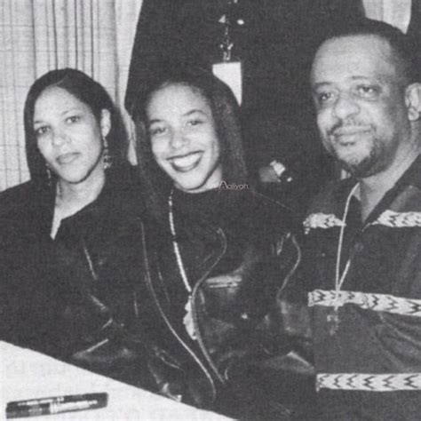 two women and a man sitting at a table smiling for the camera, in black and white