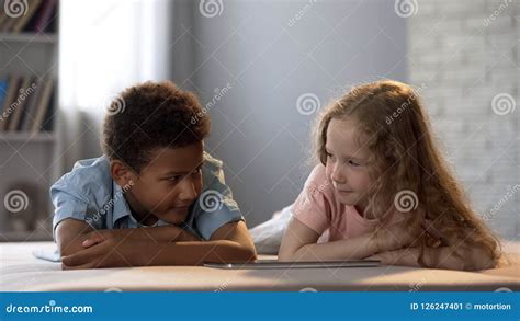 Children Watching Show on Tablet Hesitantly, Looking at Each Other Embarrassing Stock Image ...