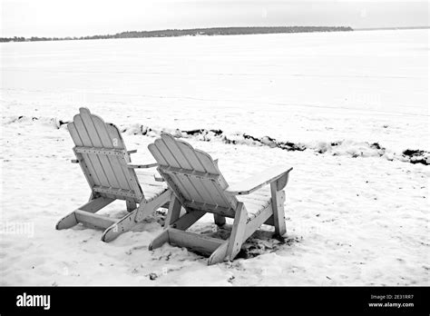 Grayscale shot of wooden garden chairs in a snowy forest Stock Photo - Alamy