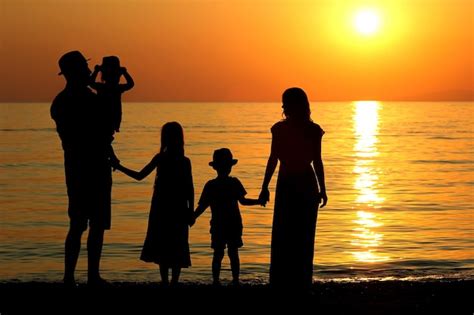 Premium Photo | Family silhouette at sunset by the sea in summer