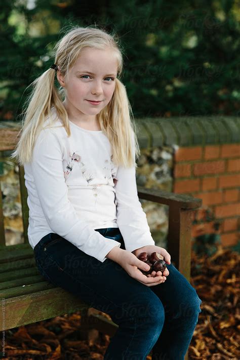 "A Little Girl Sitting Outdoors With Her Hands Full Of Conkers." by Stocksy Contributor "Helen ...