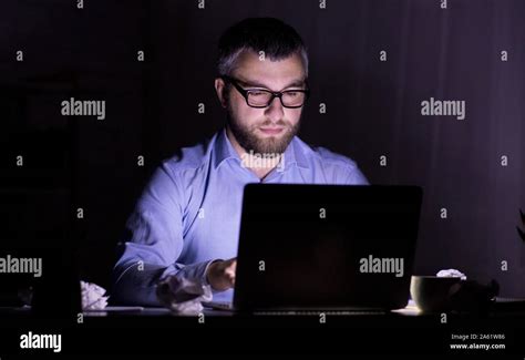 Puzzled man looking at laptop screen in dark room Stock Photo - Alamy