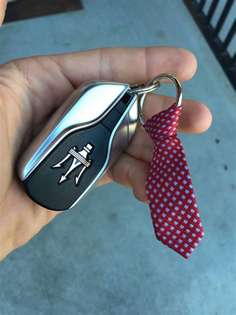 a hand holding a keychain with a red tie on it