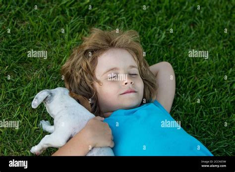 Little child lying on the lawn of a garden is cuddling puppy dog Stock Photo - Alamy