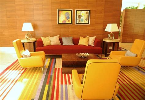 Lounge room, sofas, pillows, armchairs, end tables, lamps, art, wood walls, striped carpet, red ...