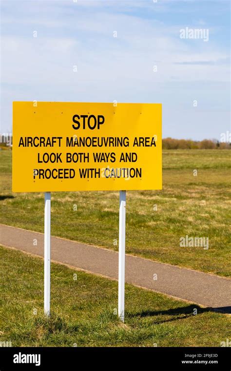 Yellow Airfield warning sign. Stop. Aircraft manoeuvering area. Look both ways and proceed with ...