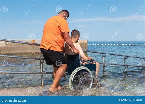 Man on Wheelchair on Ramp To Sea Stock Image - Image of help, lifeguard: 229871137