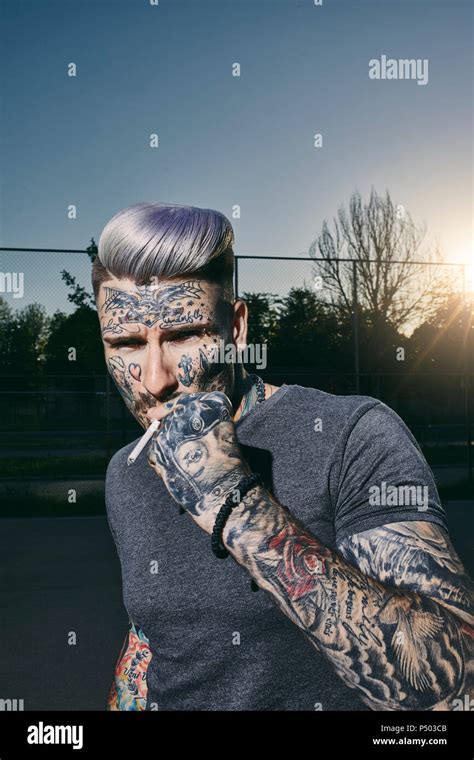 Portrait of tattooed young man smoking a cigarette Stock Photo - Alamy