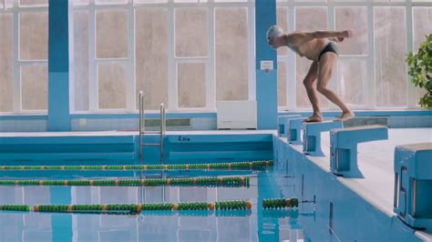 Senior man in an indoor swimming pool. Active pensioner enjoying sport. An old man jumping in ...