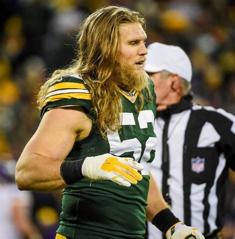 a man with long hair wearing a green and yellow uniform standing next to a referee