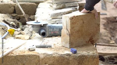 A stonecutter or stonemason is profiling the cut of a stone with a wide ...