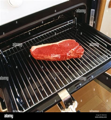 Raw Sirloin Steak on a Grill Pan being placed under an oven grill in a ...