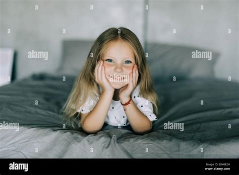 Portrait of cute girl lying barefoot in the bed Stock Photo - Alamy