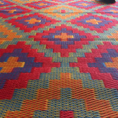 a multicolored rug on the floor with a person standing next to it