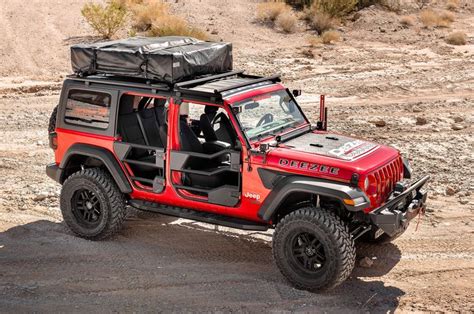 a red jeep with a black top and luggage on it's roof in the desert