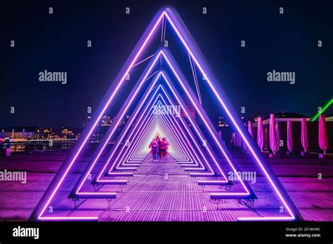 Purple coloured gate of light or light tunnel installation made of triangular neon and led ...