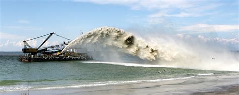 Work dredger dredging with sand washing on beaches. Special dredging hose for sand to create new ...