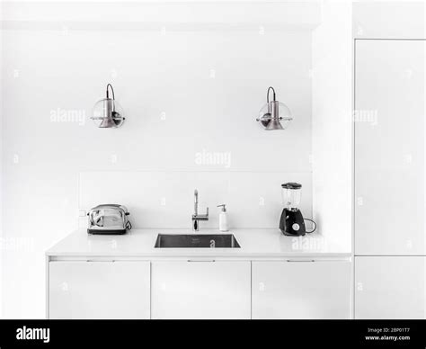 New stylish bright kitchen with white cabinets. Spacious modern interior with metal sink, retro ...