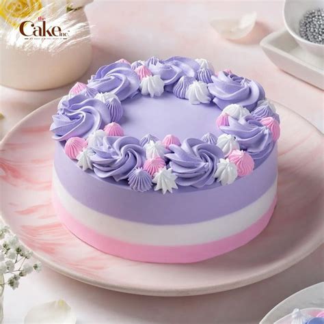 a purple and white cake on a pink plate with flowers in the middle, next to other plates