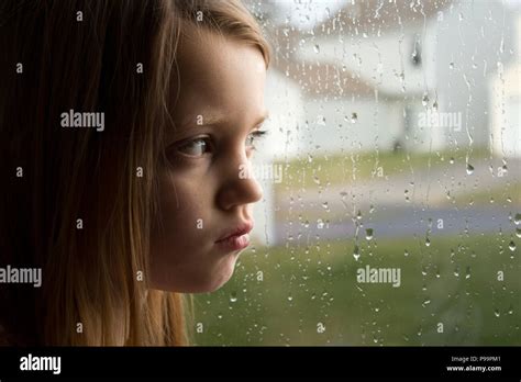 Sad little girl staring out rainy window hi-res stock photography and images - Alamy