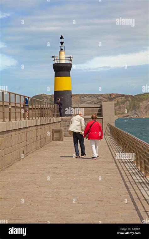 Man and woman walking hand in hand towards the lighthouse on the ...