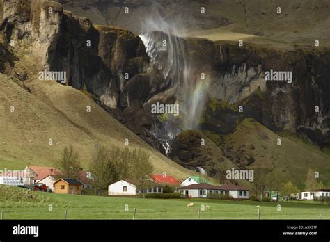 Waterfall near the farming village of Horgsland in Iceland with a rainbow in the water spray ...