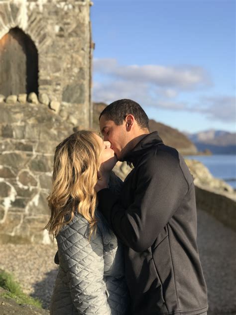 a man and woman standing next to each other in front of a stone ...