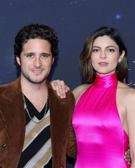 a man and woman standing next to each other in front of a blue wall ...