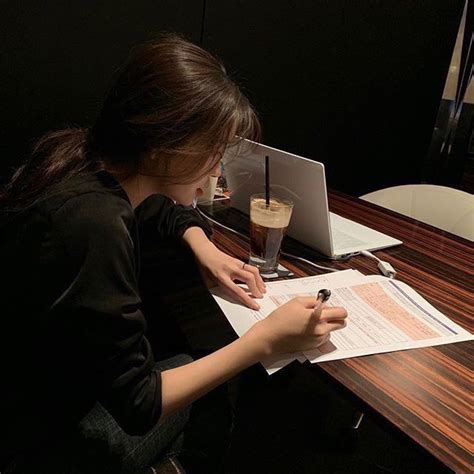 a woman sitting at a desk writing on a piece of paper