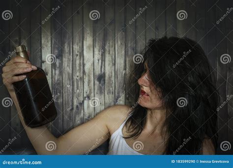 A Young Drunk Woman Looks at the Bottle of Alcohol with Interest. Stock ...