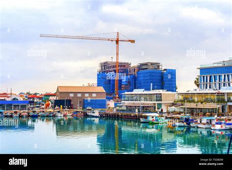 Construction site by Limassol waterfront, boats moored in marina with cafes and restaurants ...