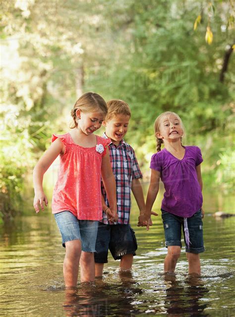 Three kids (4-5, 6-7) holding hands and walking together in small ...