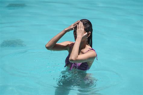 Sensual young lady touching wet hair in pool during summer holidays ...