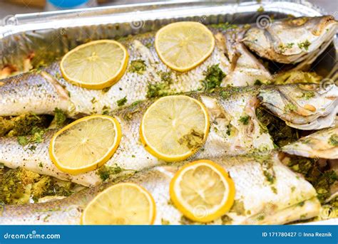 Cooking a Fresh Sea Bass with Lemon, Garlic and Herbs. Stock Image ...