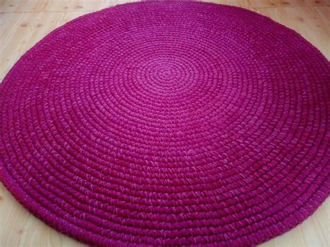 a large round rug on the floor with wood floors in the background and pink yarn