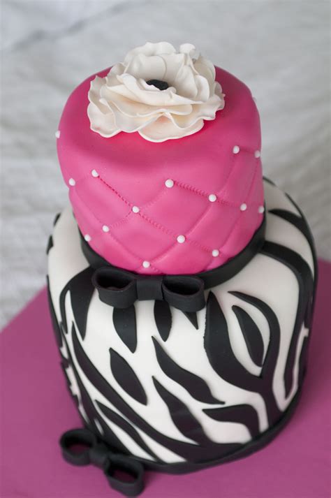 two tiered cake decorated with zebra print and pink icing, topped with ...