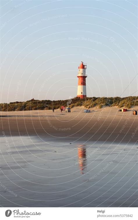 Lighthouse on Borkum beach with reflection in water, dunes and beach tents - a Royalty Free ...