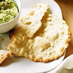 a white plate topped with crackers next to a bowl of dip and guacamole