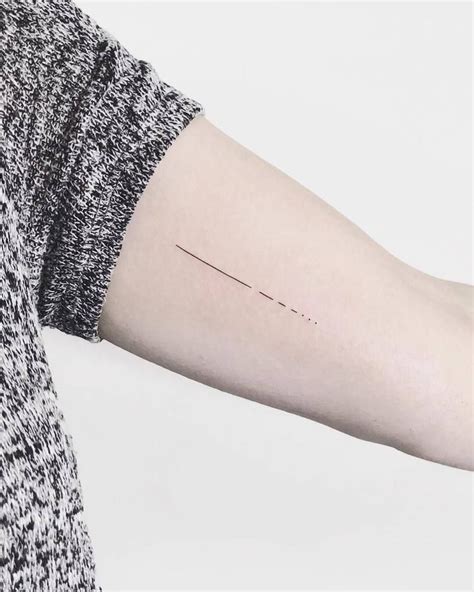Disappearing black thin dotted and dashed line tattoo inked on the left bicep | Minimalist ...