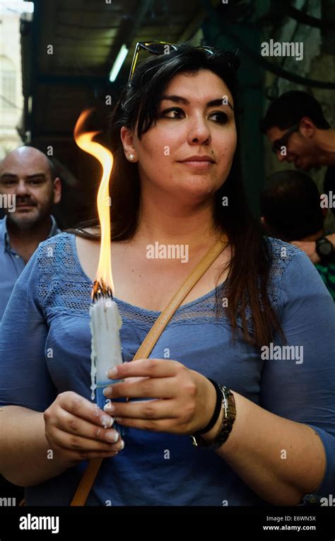 Woman cleans her hands from the wax of the candles during Holy Fire ceremony in Jerusalem ...