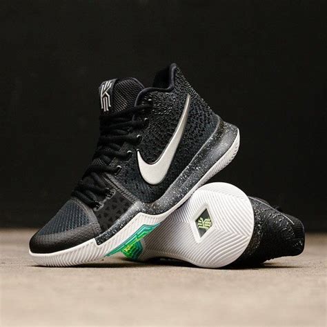 a pair of black and white shoes with green accents on the upper part of the shoe