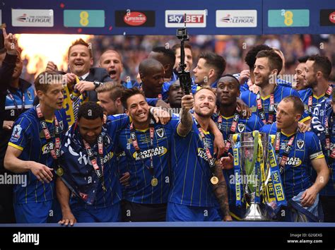 AFC Wimbledon players celebrate with the Sky Bet League Two Trophy ...