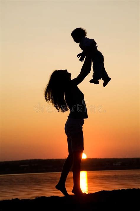 Photo about Silhouette of mother which turns the child against a sunset ...