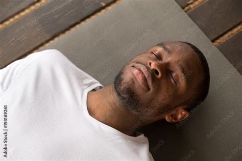 Photo of young black man lying in Dead Body exercise or Corpse pose with his eyes closed ...